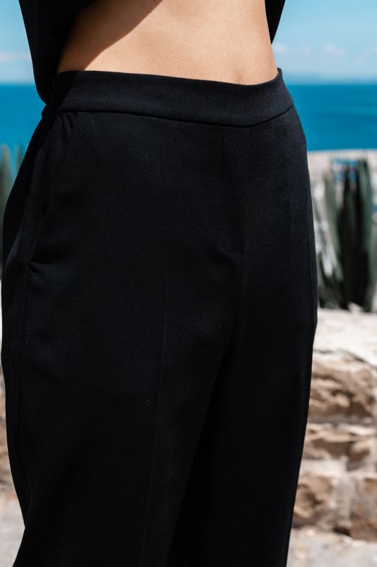Détails du pantalon noir, une pièce polyvalente et élégante.