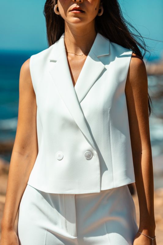 Détails du gilet : Couleur blanche et fermeture à deux boutons.