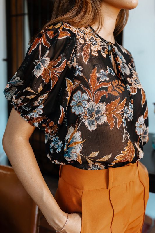Gros plan sur le motif délicat et raffiné de la blouse, parfait pour un style automnal.