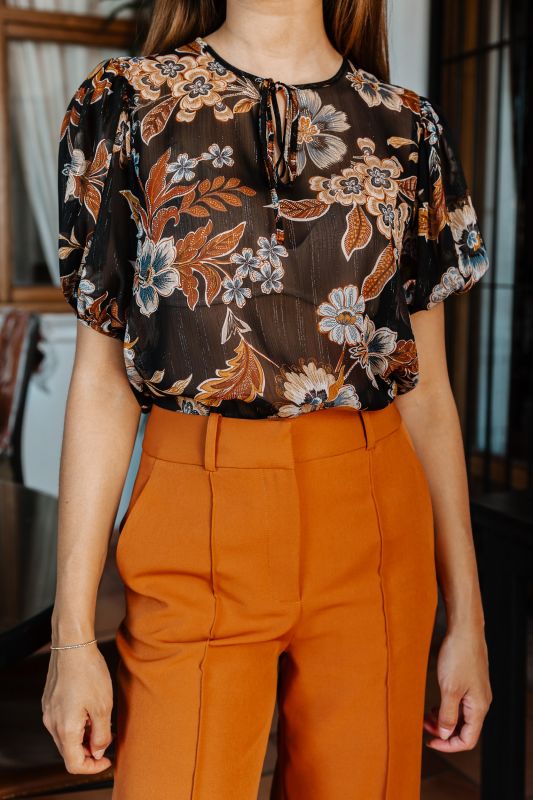 Blouse élégante avec des fleurs sur un fond noir.