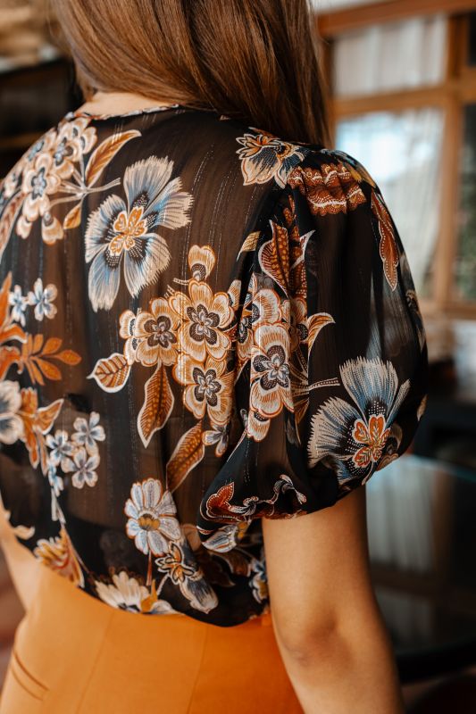 Blouse élégante avec des fleurs sur un fond noir.