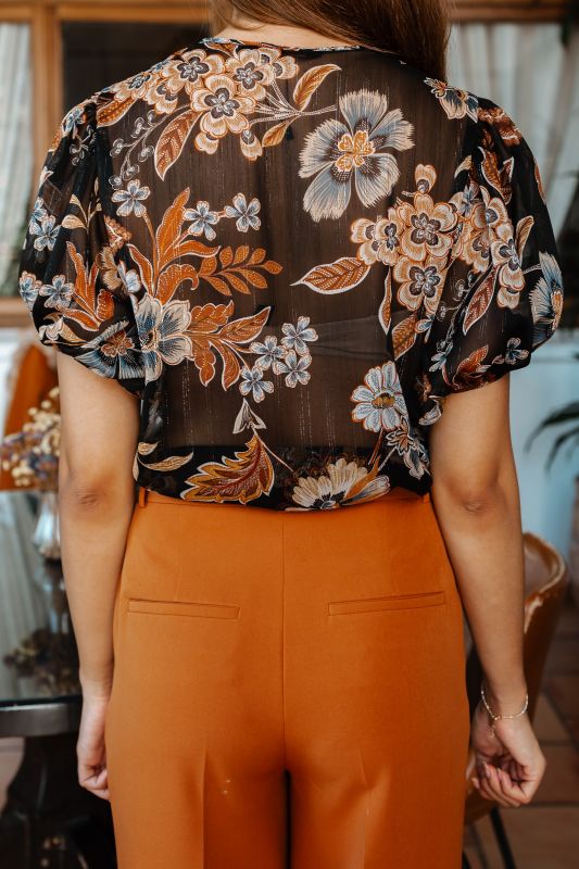 Blouse élégante avec des fleurs sur un fond noir.