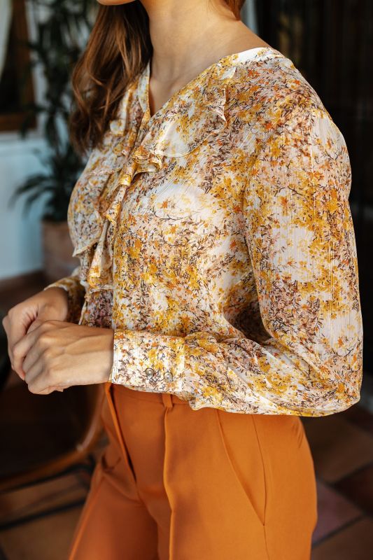 Zoom sur la texture et le tissu de la blouse imprimée, combinant confort et style.