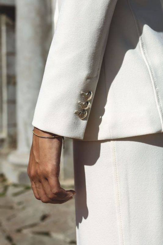Gros plan sur les manchettes d'un blazer ANAE blanc, mettant en vedette des boutons délicats.