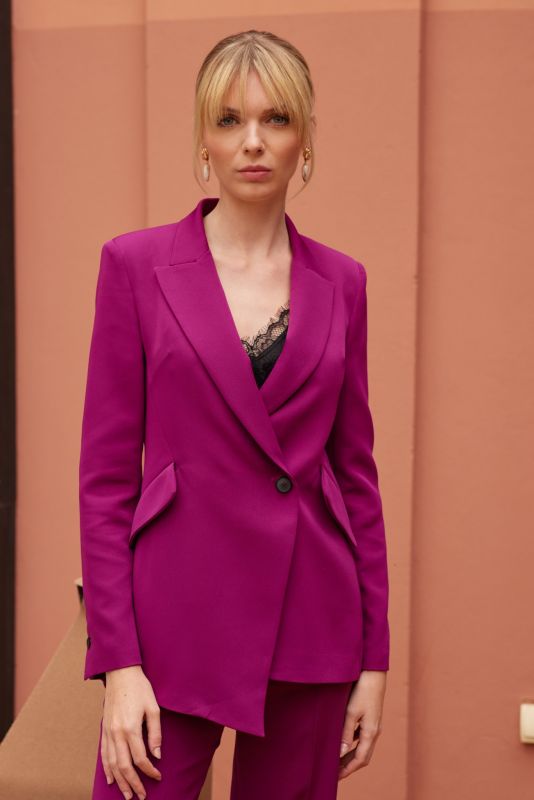 Élégance décontractée avec la veste Darren fuchsia de la collection Fiesta 24 d'ANAE, devant un fond architectural.