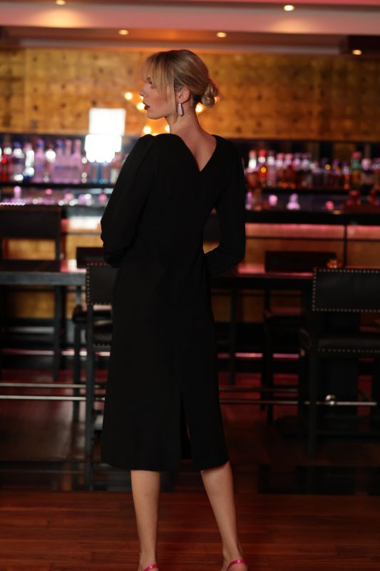 Femme chic en ROBE MARISSA noire, collection FIESTA 24 d'ANAE, avec pochette métallique, ambiance bar élégant.
