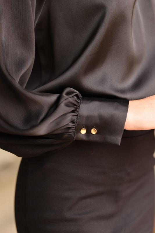 ANAE dépeint le charme subtil avec la blouse Harmony noire, un incontournable pour une tenue professionnelle chic.