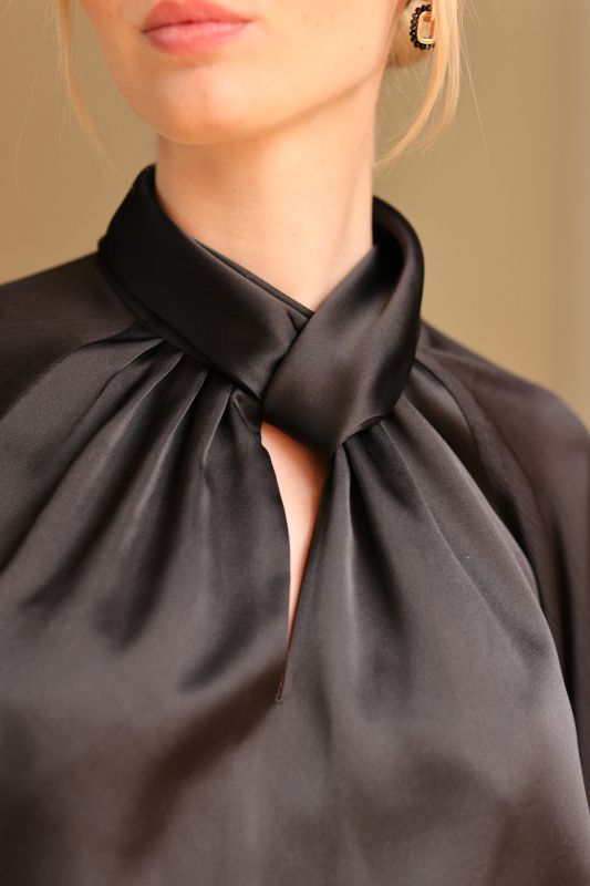 Élégance intemporelle avec la blouse noire à col noué Harmony d'ANAE, reflétant une sophistication discrète.