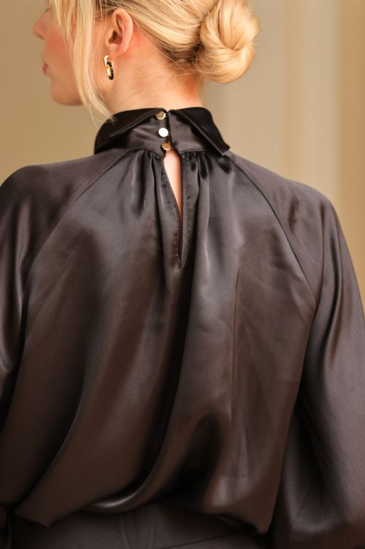 ANAE dépeint le charme subtil avec la blouse Harmony noire, un incontournable pour une tenue professionnelle chic.
