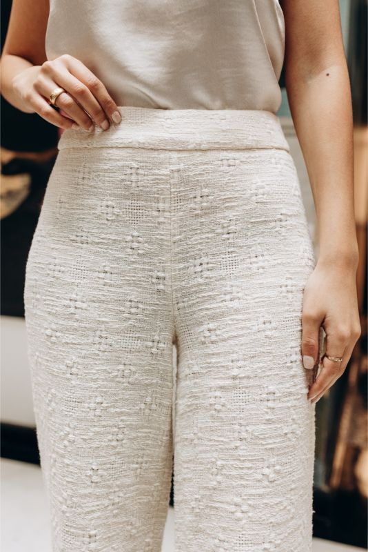 Gros plan sur un pantalon en tweed blanc ANAE, mettant en évidence la texture et la coupe soignée pour un style intemporel.