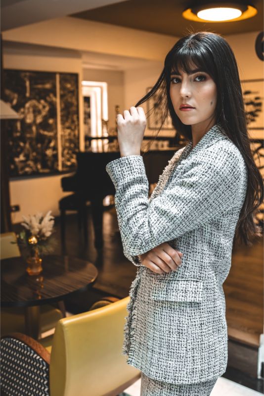 Plan rapproché d'une veste en tweed gris et blanc avec détail de frange sur le col.