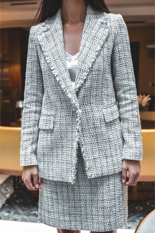 Gros plan sur le bouton de la veste de tweed ANAE, mettant en avant les détails élégants et la finition de haute qualité.
