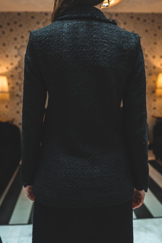 Gros plan sur le tweed noir de la veste ALISIA TWEED 24 d'ANAE, mettant en évidence la qualité du tissu et le bouton détaillé.