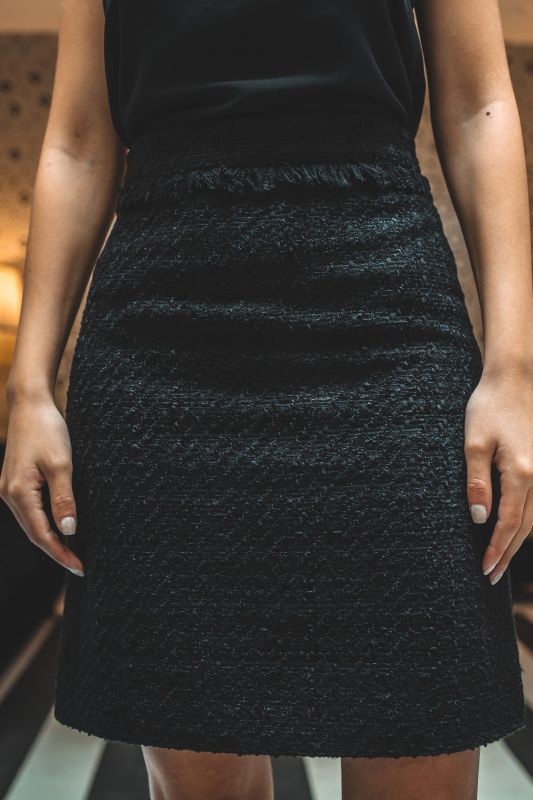 Gros plan sur la jupe ALISIA TWEED 24 d'ANAE, mettant en évidence la texture délicate du tweed et l'ourlet frangé tendance.