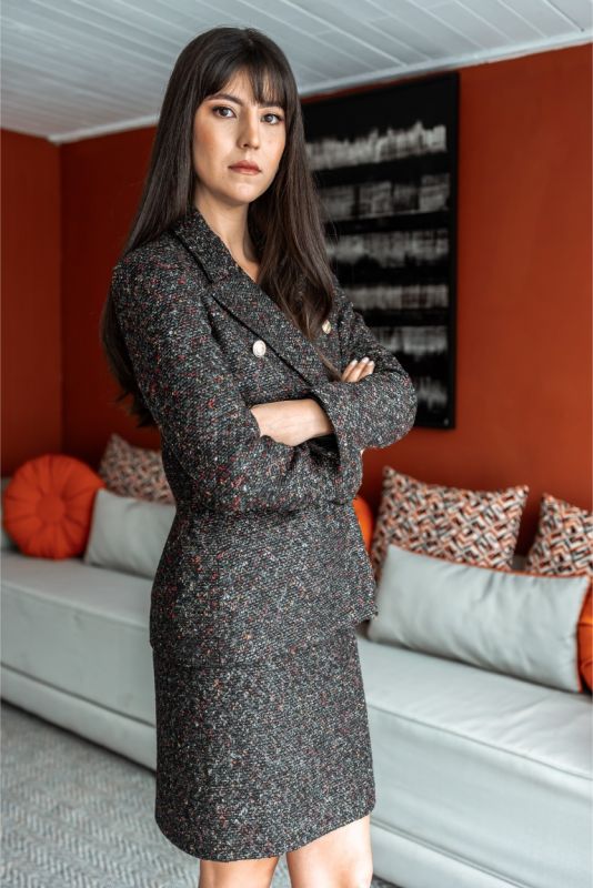 Femme élégante assise, portant la robe PRECIOUS en tweed noir et blanc d'ANAE, incarnant un style chic et intemporel.