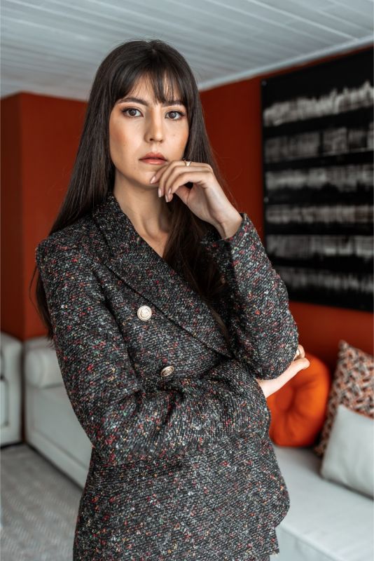 Robe de tweed noir et blanc ANAE avec boutons détaillés, démontrant une sophistication moderne dans un cadre intérieur stylé.