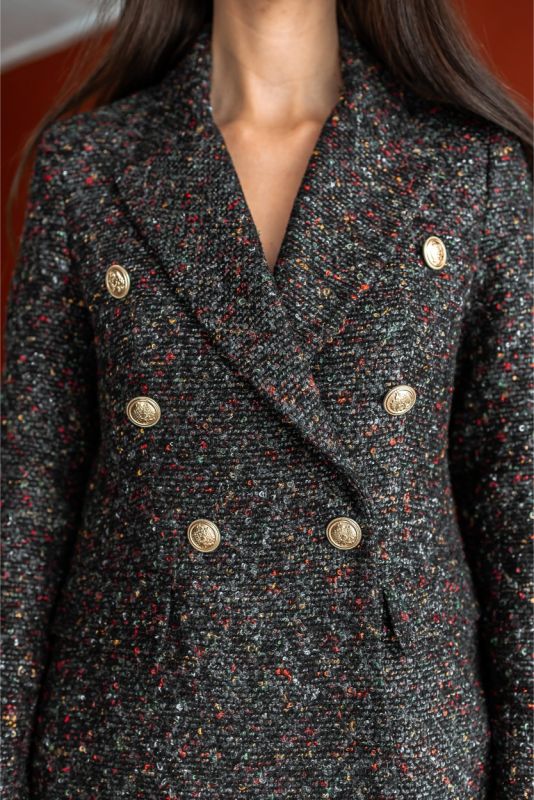 Robe de tweed noir et blanc ANAE avec boutons détaillés, démontrant une sophistication moderne dans un cadre intérieur stylé.