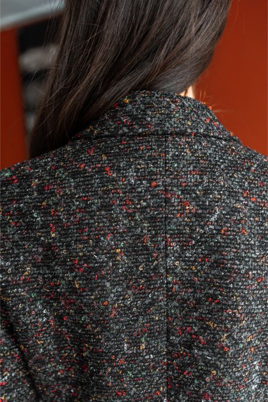 Vue de dos d'une femme en robe de tweed noir et blanc ANAE, mettant en valeur la coupe ajustée et le motif texturé élégant.
