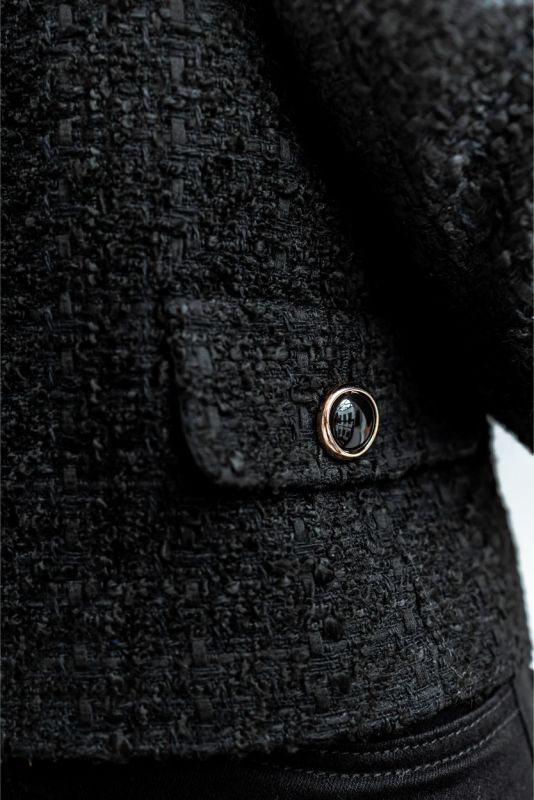 Détail de la veste en tweed noir ALYANA d'ANAE, montrant la texture riche et les poches plaquées pour une touche fonctionnelle.