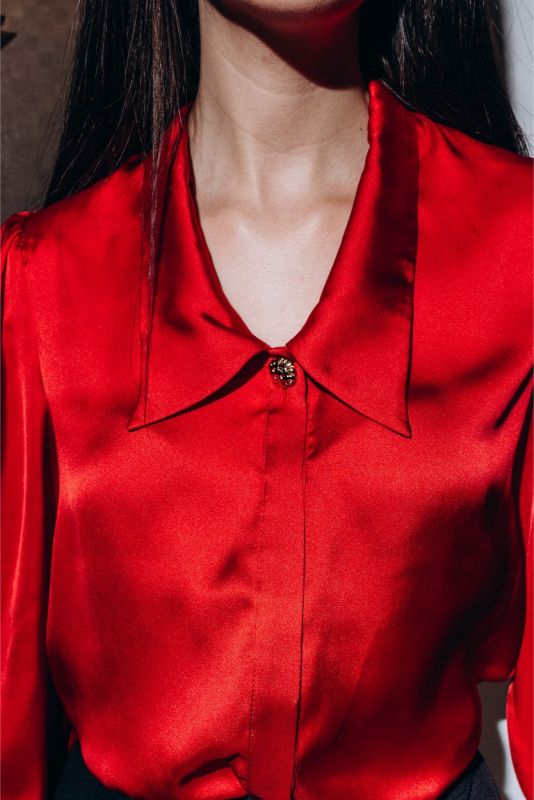 Close-up d'une chemise rouge Hardenberg ANAE, montrant les boutons dorés délicats sur le poignet, symbole de raffinement.
