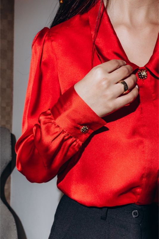Close-up d'une chemise rouge Hardenberg ANAE, montrant les boutons dorés délicats sur le poignet, symbole de raffinement.
