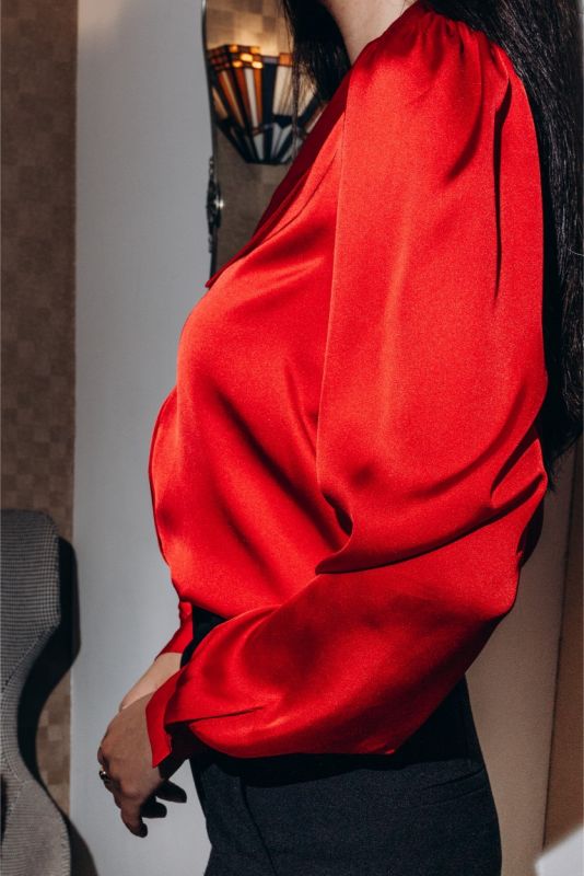 Détail d'une chemise rouge ANAE avec manchettes élastiques et boutons dorés, soulignant une attention méticuleuse aux détails