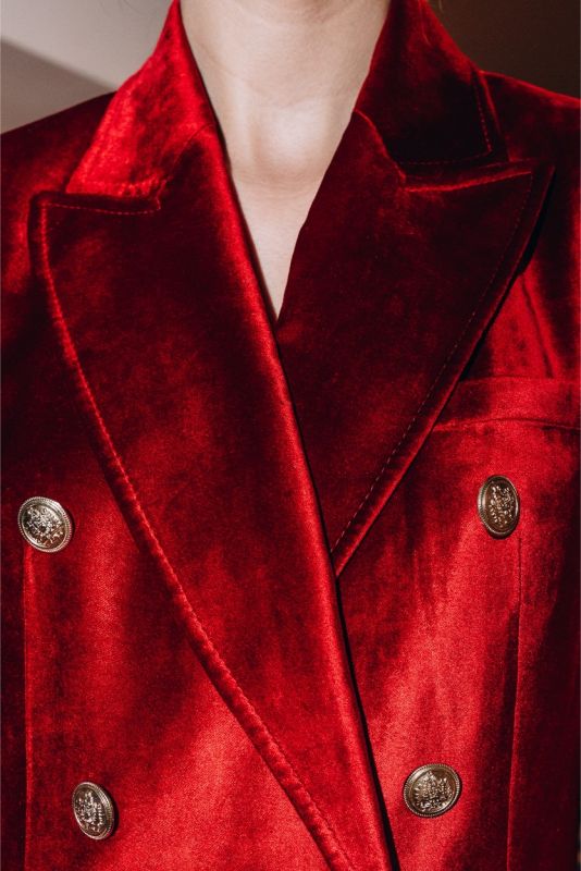 Détail d'une veste en velours rouge ANAE avec boutons argentés, incarnant une sophistication luxueuse et un style intemporel.