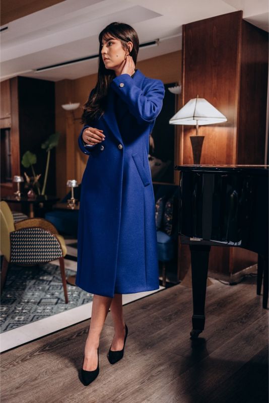 Vue latérale d'une femme portant le manteau Chaouen bleu vibrant d'ANAE, mettant en valeur son design épuré.