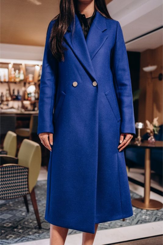 Manteau long bleu Chaouen d'ANAE boutonné, reflétant un style minimaliste et une élégance moderne.