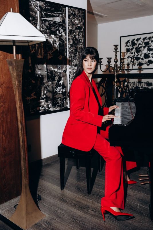 Portrait d'une femme vêtue d'une veste rouge éclatant de la collection ANAE, reflétant un style chic et audacieux.