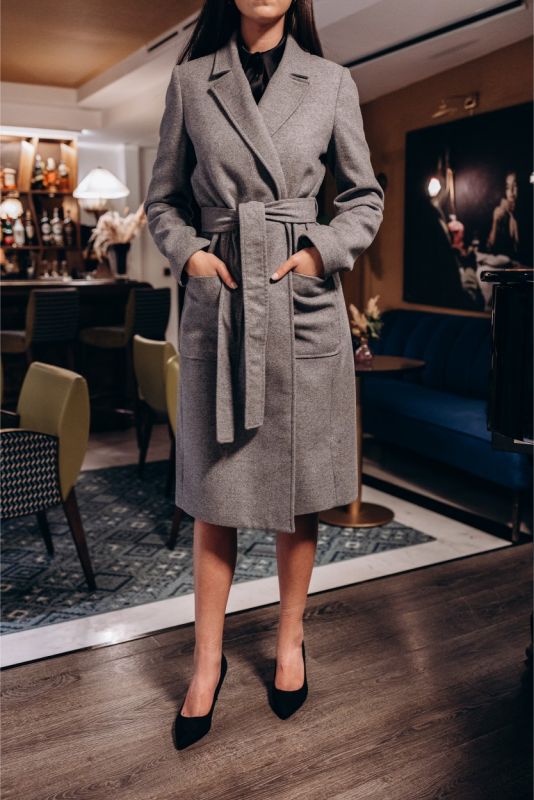 Manteau gris Malaga d'ANAE avec une fermeture croisée élégante et une ceinture assortie accentuant la silhouette.