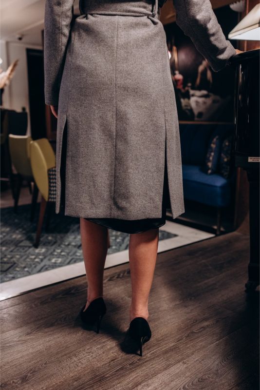 Focus sur la poche plaquée d'un manteau ANAE gris, illustrant la fonctionnalité et le style.
