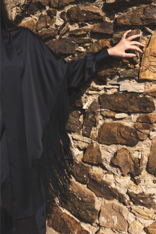 Close-up du caftan Anissa d'ANAE, accentuant les franges noires et le tissu fluide.