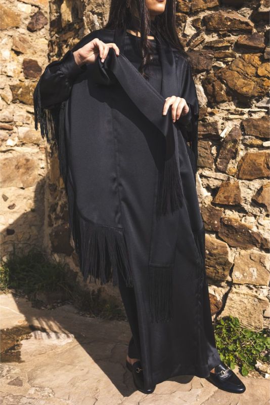Close-up du caftan Anissa d'ANAE, accentuant les franges noires et le tissu fluide.