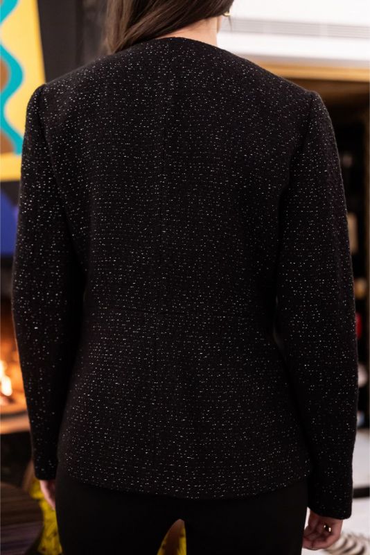 Vue arrière d'une femme portant la veste Margaret noire à détails scintillants, collection Tweed 23 d'ANAE.