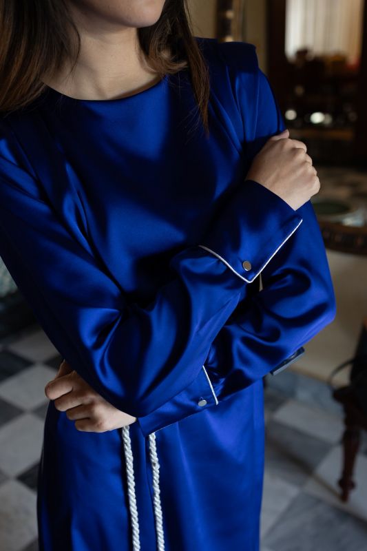 Détail du caftan SAKINA d'ANAE en bleu roi, manches avec revers et ceinture à pompons blancs.