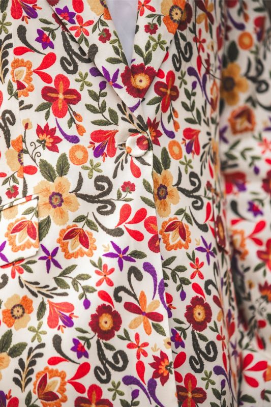 Gros plan sur le tissu de la veste JEANNA d'ANAE, montrant le détail des motifs floraux colorés.