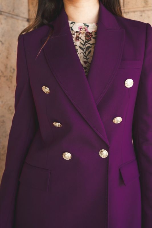 Poignet de veste Moller d'ANAE, montrant les boutons dorés et la couleur prune profonde.