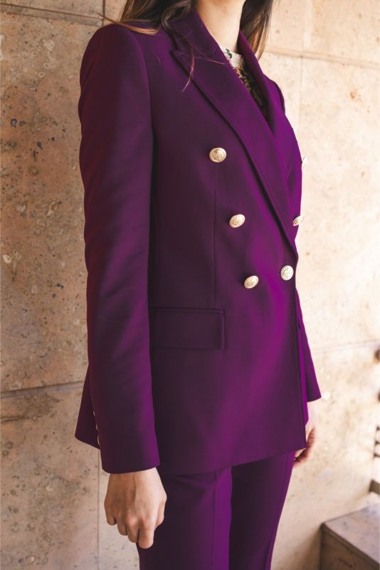 Poignet de veste Moller d'ANAE, montrant les boutons dorés et la couleur prune profonde.