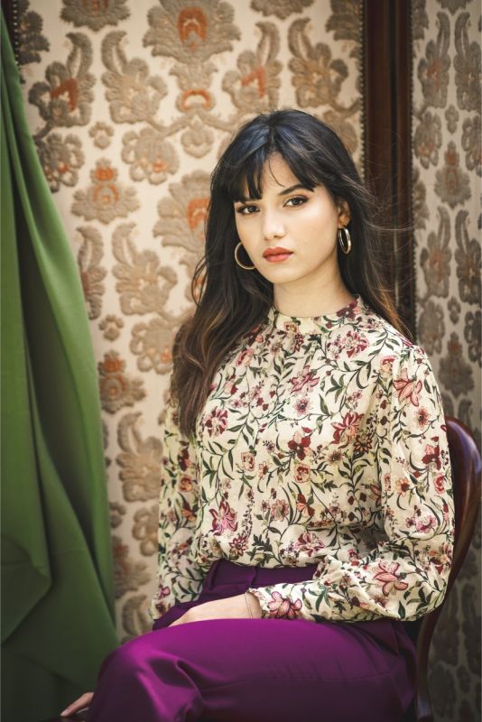 Blouse à motif floral multicolore sur fond écru, col montant et plis subtils.