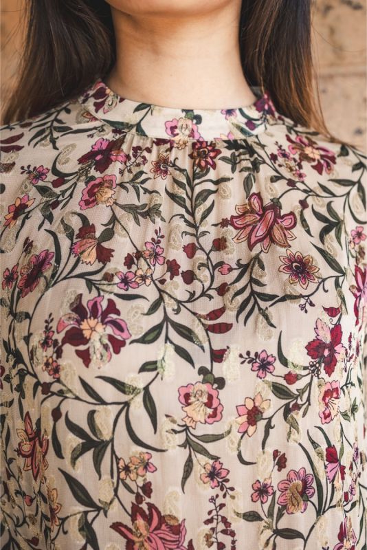 Blouse Wallin d'ANAE à manches longues avec imprimé floral, portée avec une jupe prune.