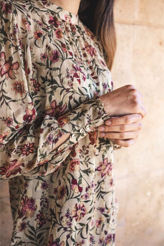 Blouse Wallin d'ANAE à manches longues avec imprimé floral, portée avec une jupe prune.