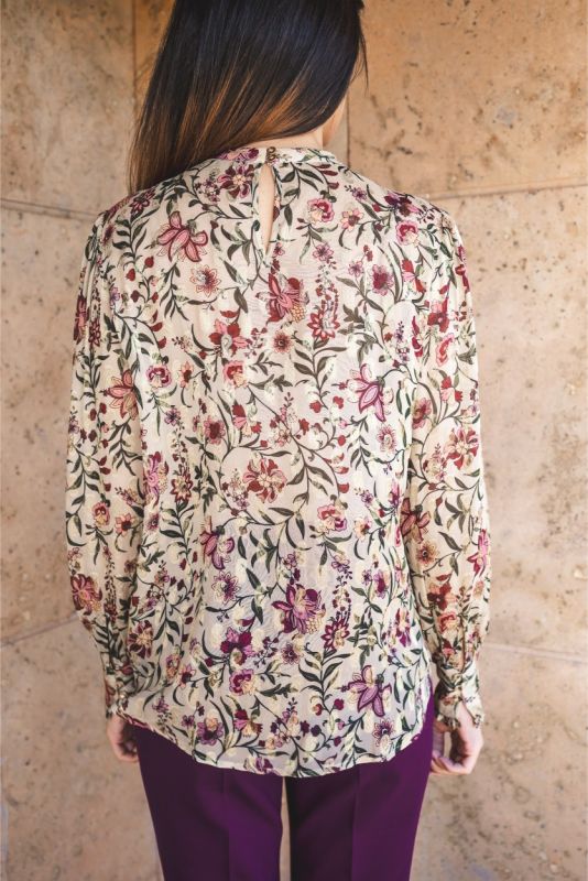 Blouse Wallin d'ANAE à manches longues avec imprimé floral, portée avec une jupe prune.