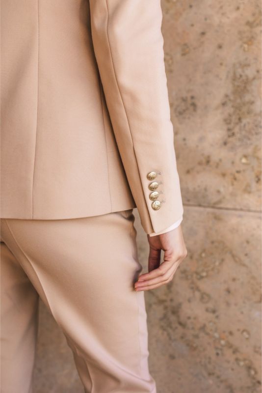 Vue arrière de la veste 'Frida' d'ANAE beige, mettant en évidence la coupe ajustée et les détails des manches pour un look chic.