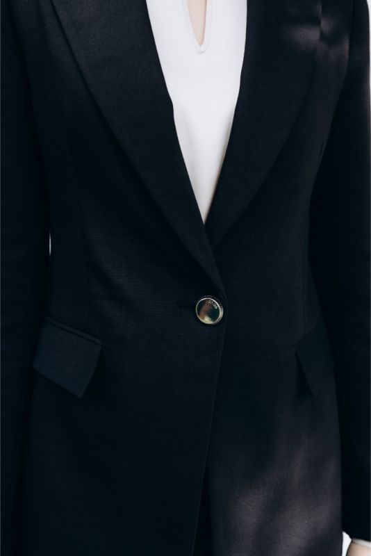 Détail de la veste 'Lorena' ANAE : bouton unique doré, équilibre parfait entre minimalisme et sophistication.