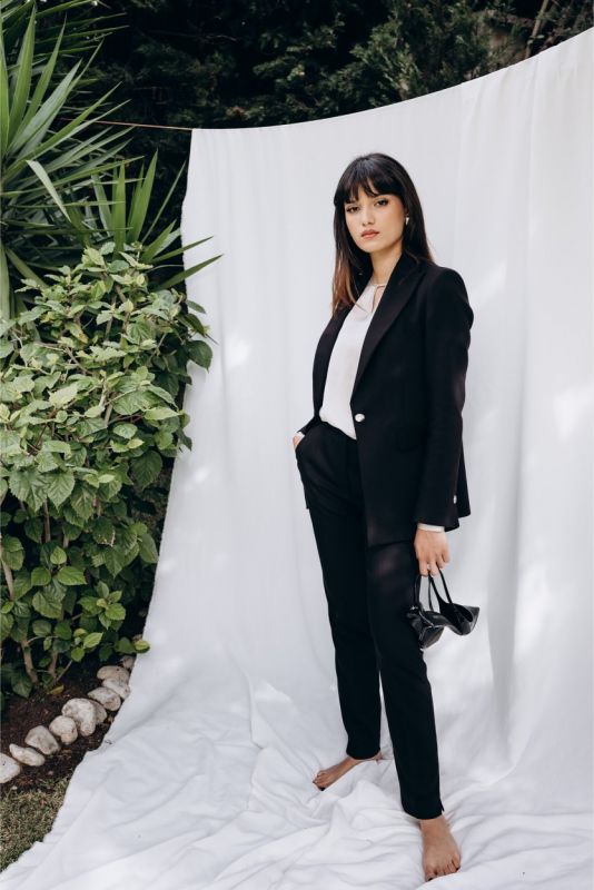 Femme chic en veste noire 'Lorena' d'ANAE, alliance de confort et d'élégance naturelle, prête pour toute occasion.