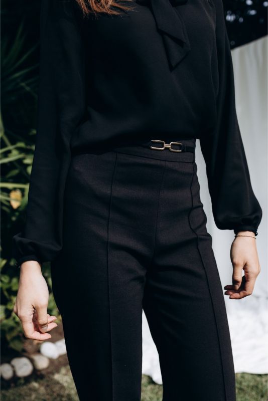 Zoom sur le pantalon noir structuré ANAE avec détail de ceinture métallique, parfait pour une silhouette affinée.