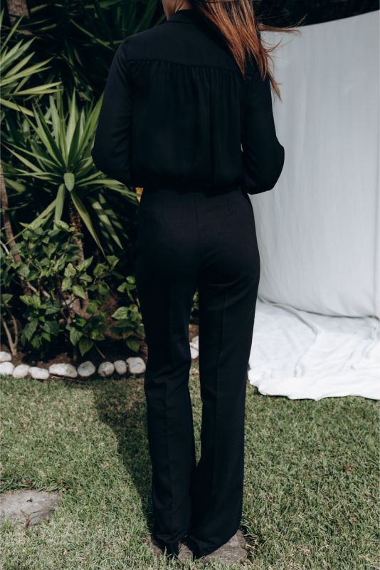 Dos du pantalon noir ANAE, accentuant la taille cintrée et le tombé impeccable sur des talons noirs.