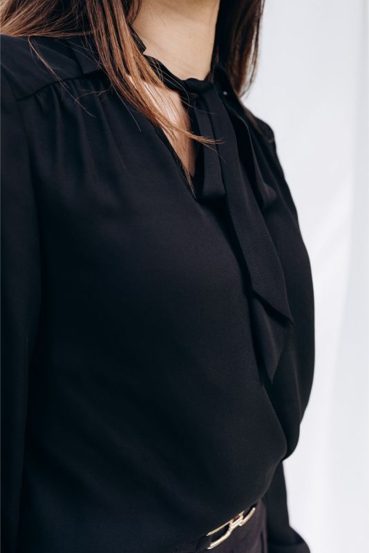 Détail de la blouse 'Belkis' d'ANAE, avec son nœud et manchettes boutonnées, épitomisant une élégance discrète.