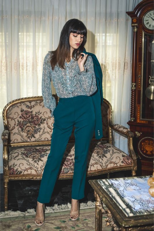 Pantalon structuré ANAE en tissu bleu émeraude avec plis marqués, combiné à des talons hauts pour une silhouette affinée.
